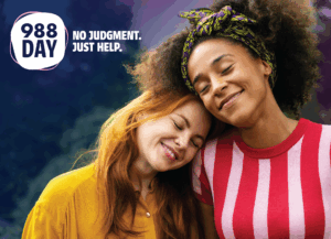 Two wmen lovingly embrace and comfort each other. Head resting on the other's shoulder. Text reads 988 Day, no judgement, no fear.