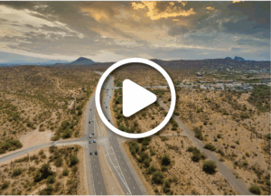 Aerial view of roads going through rural Arizona. There is a video play button overlayed on the image.